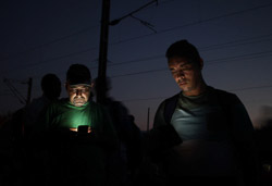 El drama dels refugiats sirians, a la frontera de Macedònia Dos refugiats mirant el mòbil mentre esperen a la frontera (25 d'agost). Foto: Sergi Cámara